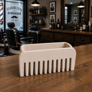 Puede incluir: Un organizador de madera de color claro en forma de peine se encuentra sobre una superficie de madera. El organizador tiene una secci&oacute;n superior rectangular y una base en forma de peine con dientes espaciados. El fondo muestra un interior de barber&iacute;a.