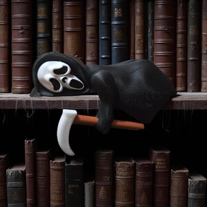 May include: A black Grim Reaper figurine with a white mask and a scythe. The figure is lying on a wooden shelf in front of a backdrop of antique books. The scythe has a white blade and a brown handle.