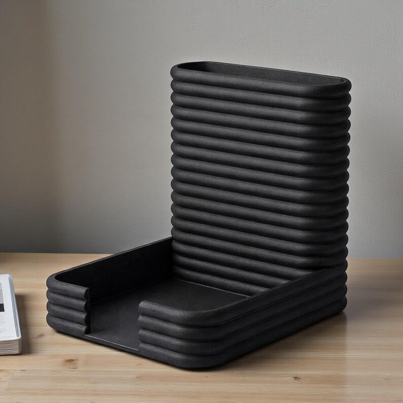 Pu&ograve; includere: Un organizer da scrivania nero con un design a coste unico. Ha una base rettangolare e uno schienale verticale curvo. Il design &egrave; moderno e minimalista, adatto per l'ufficio o la casa.