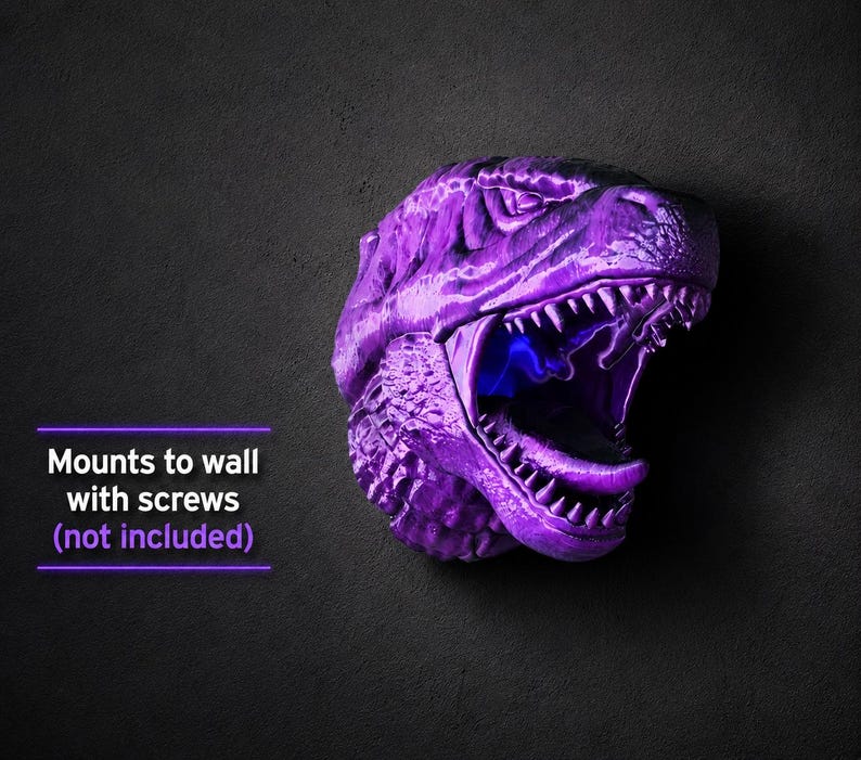 Może przedstawiać: Fioletowa głowa dinozaura do montażu na ścianie z otwartą paszczą odsłaniającą ostre zęby i niebieskie wnętrze. Tekst "Mounts to wall with screws (not included)" jest widoczny.