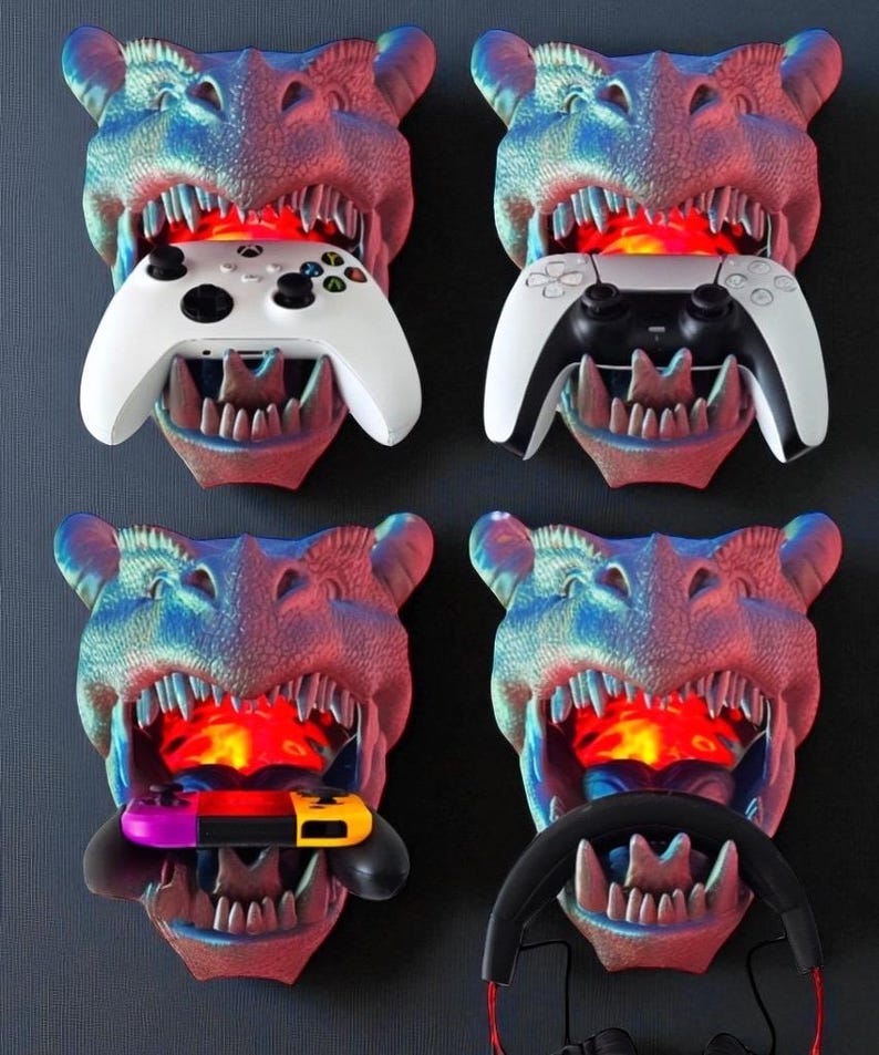 May include: Four dinosaur head-shaped wall mounts in blue, red, and purple hues, each holding a different gaming accessory: a white Xbox controller, a white and black PlayStation controller, a Nintendo Switch, and a black steering wheel with headphones.