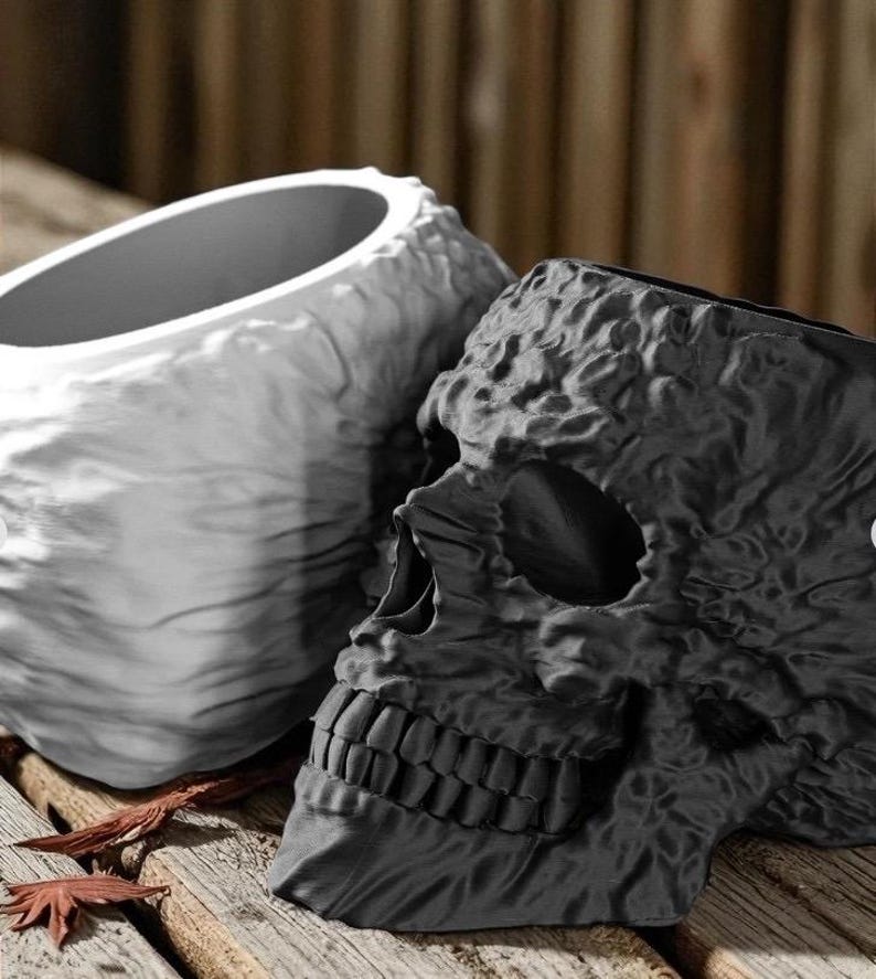 May include: Two decorative skull-shaped planters. One planter is black, and the other is white. Both planters have a textured, weathered appearance. The planters are made of a durable material and are suitable for indoor or outdoor use.