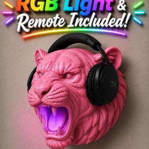 May include: A pink, sculpted tiger head with an open mouth and black headphones. The tiger's mouth glows with purple light. The text "RGB Light & Remote Included!" is displayed above the tiger's head in colorful letters.