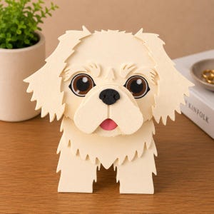 May include: A cream-colored, 3D papercraft dog figurine with large brown eyes, a black nose, and a pink tongue. The dog has detailed fur and is standing upright. The figurine is on a wooden surface.