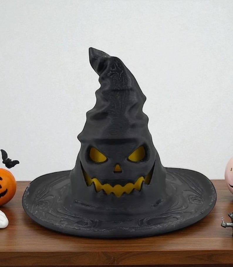 May include: A black Halloween witch hat with a carved jack-o'-lantern face. The hat has a wide brim and a tall, pointed crown. The interior glows with a yellow light, creating a spooky effect. The hat is a decorative item.