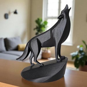 May include: A black, geometric wolf sculpture in a howling pose. The wolf is standing on a dark, oval-shaped base. The sculpture is made of a matte material and is set against a blurred background.