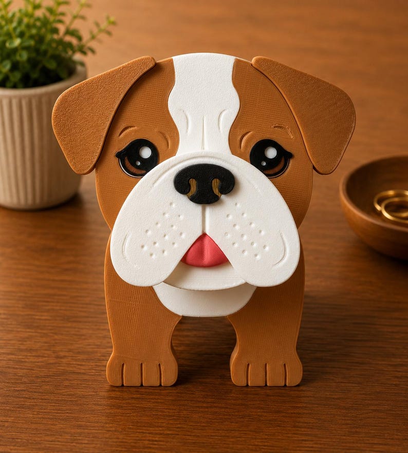 May include: A brown, white, and black bulldog-shaped decorative box. The bulldog has large, expressive eyes, a pink tongue, and a white muzzle. The box is made of a sturdy material and is designed to stand upright.