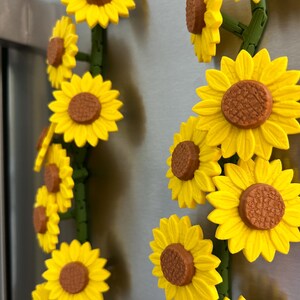 May include: Yellow sunflower magnets with brown centers and green stems. The magnets are arranged in a vertical pattern, creating a cheerful and decorative accent. These magnets are ideal for adding a touch of nature to any metal surface.