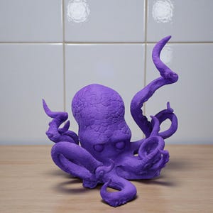 Puede incluir: Una vibrante escultura de pulpo morado con texturas detalladas. El pulpo tiene m&uacute;ltiples tent&aacute;culos rizados y una cabeza redondeada. La escultura est&aacute; sobre una superficie de madera contra un fondo de azulejos blancos. Un objeto decorativo.