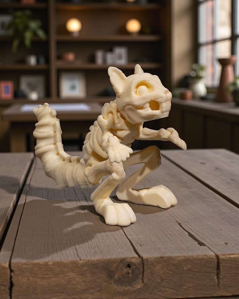 May include: A cream-colored, skeletal figurine of a cat-like creature, posed on a wooden table. The sculpture has detailed bone structure and is posed in a crouching position. The background includes a blurred interior with shelves and windows.