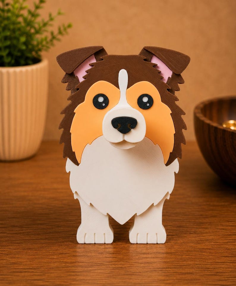May include: A layered, three-dimensional dog figurine with a brown, tan, and white color scheme. The dog has large, black eyes, a white muzzle, and a fluffy, textured appearance. The figurine is standing upright.