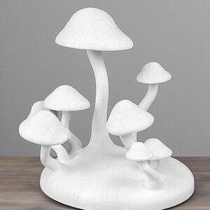 May include: A white mushroom sculpture with multiple mushroom caps of varying sizes. The sculpture is on a wooden surface and has a textured appearance. The mushrooms are clustered together, creating a whimsical decorative piece.