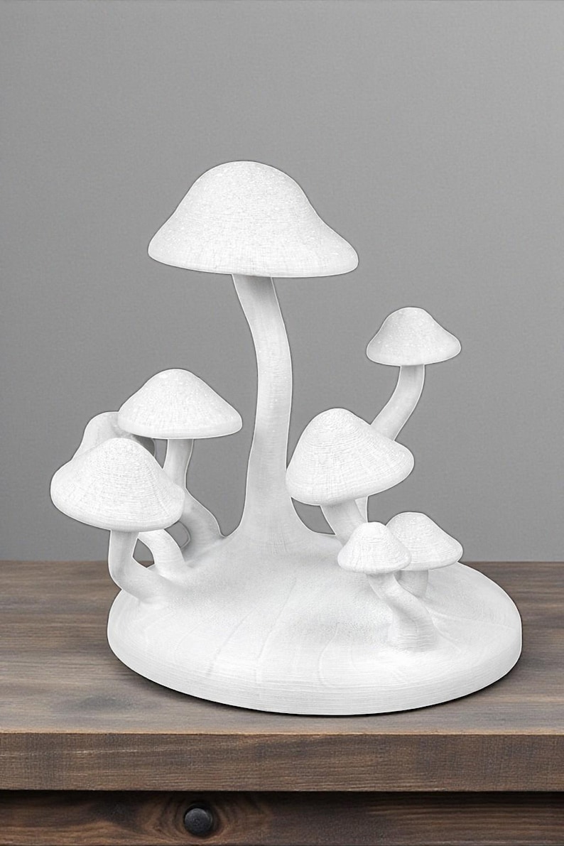 May include: A white mushroom sculpture with multiple mushroom caps of varying sizes. The sculpture is on a wooden surface and has a textured appearance. The mushrooms are clustered together, creating a whimsical decorative piece.