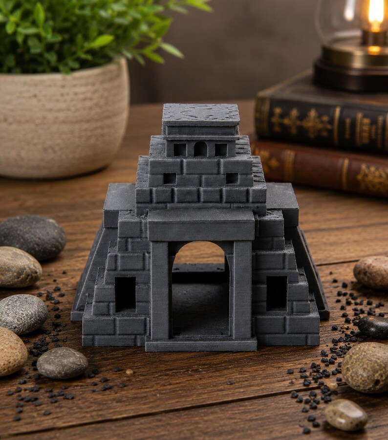 Puede incluir: R&eacute;plica gris en miniatura de un templo con dise&ntilde;o escalonado. El modelo presenta una entrada arqueada, ventanas rectangulares y un techo plano. La estructura est&aacute; hecha de un material similar a la piedra y se asienta sobre una superficie de madera.