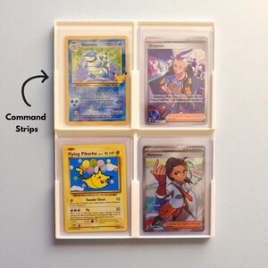 May include: A white plastic card holder with four compartments, each holding a different Pokémon trading card. The cards feature colourful illustrations of characters like Blastoise and Pikachu, with text including "Flying Pikachu" and "Thunder Shock".