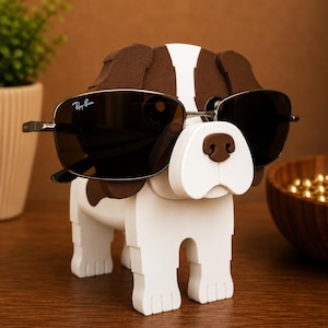 May include: A wooden dog-shaped sunglasses holder, painted white with brown spots and accents. The dog is wearing a pair of Ray-Ban sunglasses with dark lenses. The holder is on a wooden surface.