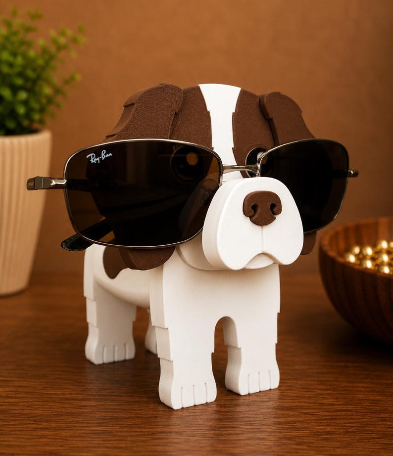 May include: A wooden dog-shaped sunglasses holder, painted white with brown spots and accents. The dog is wearing a pair of Ray-Ban sunglasses with dark lenses. The holder is on a wooden surface.