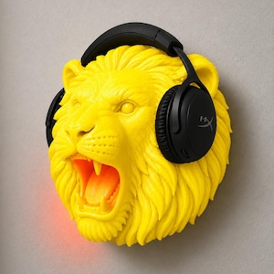 Puede incluir: Escultura de cabeza de le&oacute;n amarilla brillante con la boca rugiendo, con auriculares negros. Los auriculares tienen el logotipo de HyperX. La boca del le&oacute;n brilla en naranja y una luz roja emana de la parte inferior. La escultura est&aacute; montada en una pared gris.