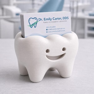 Może przedstawiać: Biały, w kształcie zęba wizytownik z uśmiechniętą twarzą. Uchwyt zawiera wizyt&oacute;wki dla Dr. Emily Carter, DDS, Family & Cosmetic Dentistry. Karty mają niebieskie i zielone logo.
