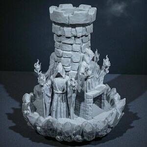K&ouml;nnte beinhalten: Ein grauer Fantasy-Duftbrenner mit einem Burgturm, zwei vermummten Figuren mit Fackeln und einem felsigen Sockel. Der Turm hat eine zinnenbewehrte Spitze und besteht aus einem steinartigen Material. Die Figuren scheinen Zauberer zu sein.