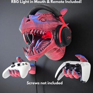 May include: A red and pink dragon head wall mount with a headset and two game controller holders. The dragon's mouth has an RGB light. Text on the image reads: "RBG Light in Mouth & Remote Included!" and "Screws not included."