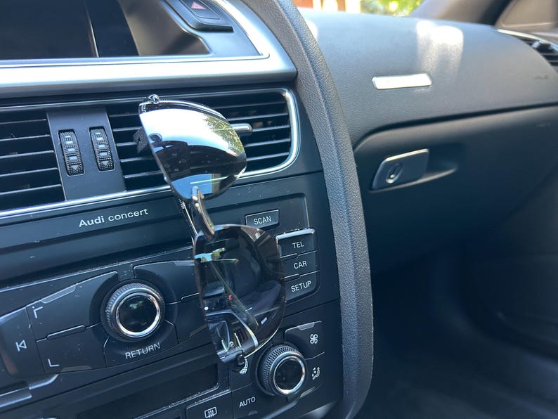May include: A close-up of a car's dashboard with a pair of sunglasses clipped to the air vent. The dashboard features buttons labeled "Audi concert", "Scan", "Tel", "Car", and "Setup".
