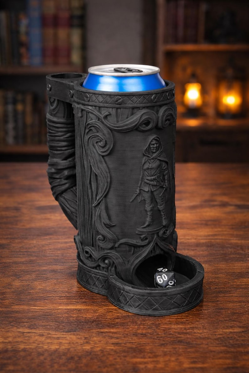 May include: Black, intricately carved beer stein with a blue can inside. The stein features a detailed relief of a hooded figure and a dice tray. The design includes floral and wood-like textures, perfect for tabletop gaming.