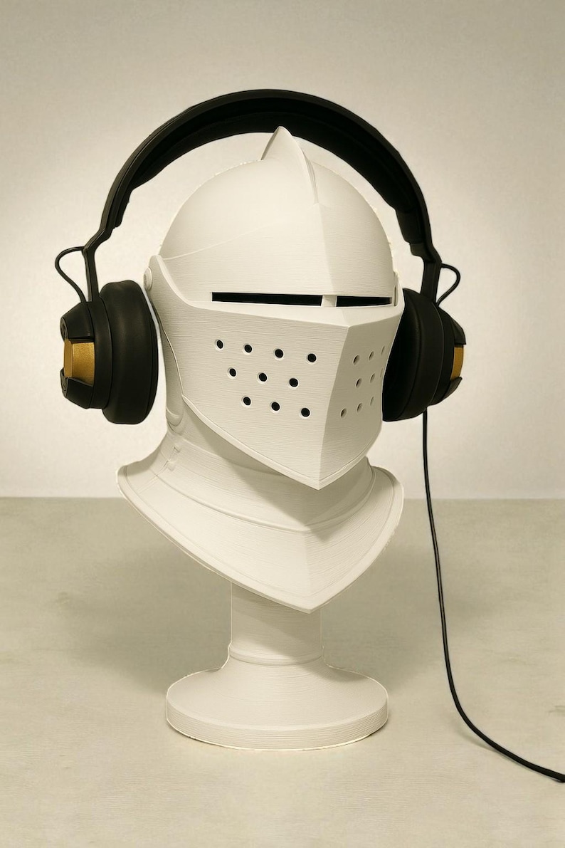 May include: A white knight's helmet bust with black headphones. The headphones have gold accents on the earcups. The helmet features a visor with small holes and a neck guard. A black cable extends from the headphones.