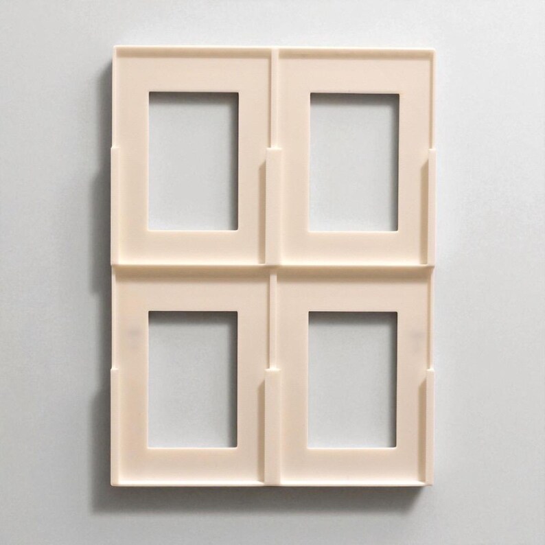 Pu&ograve; includere: Quattro cornici quadrate color crema disposte in una griglia 2x2. Ogni cornice ha un'apertura rettangolare al centro. Le cornici sono realizzate in un materiale liscio e opaco e sono progettate per contenere fotografie o opere d'arte.