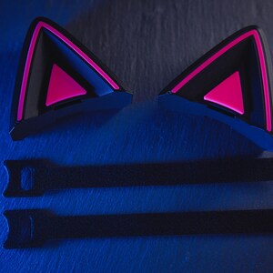 May include: Two black cat ear headphones with pink accents and two black velcro straps.