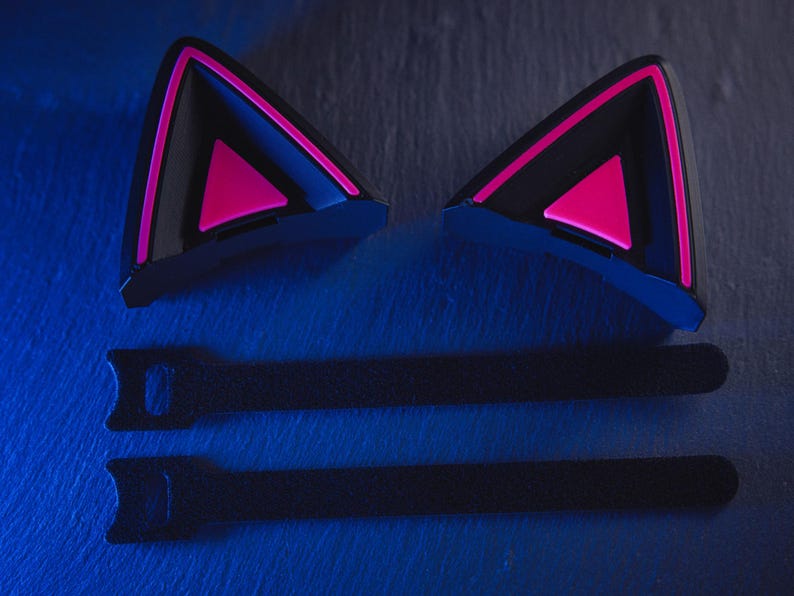 May include: Two black cat ear headphones with pink accents and two black velcro straps.