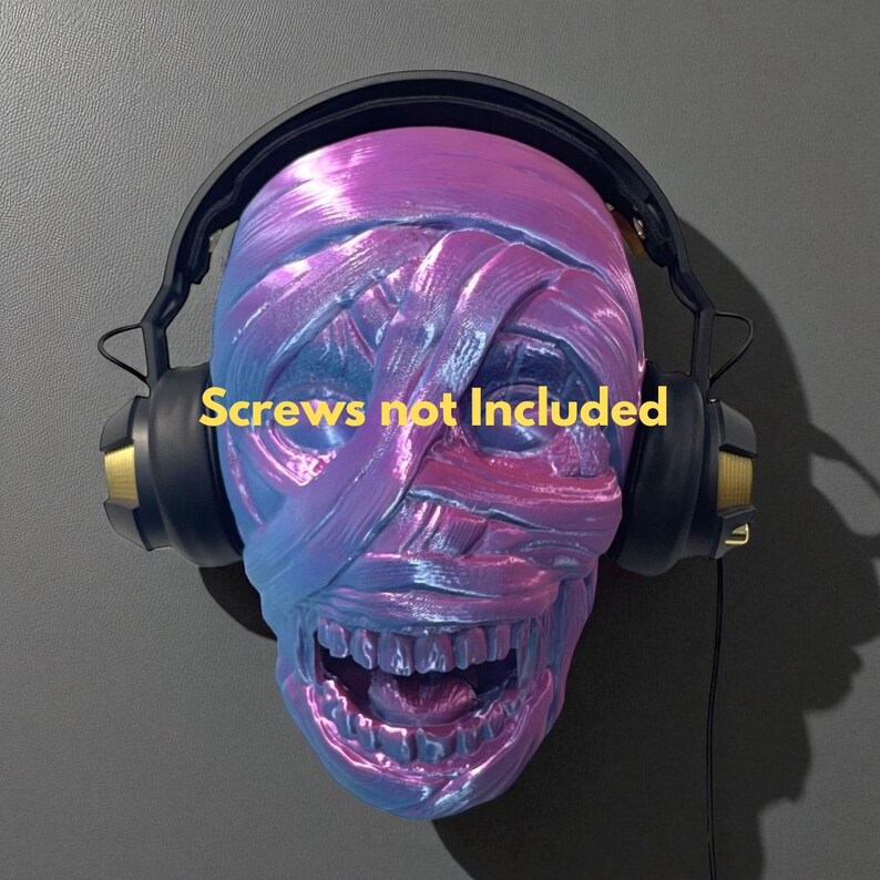 May include: A sculpted skull with a mummy-like wrap design, painted in shades of blue and purple, wearing black and gold headphones. The text "Screws not Included" is displayed. This unique piece is a decorative item.