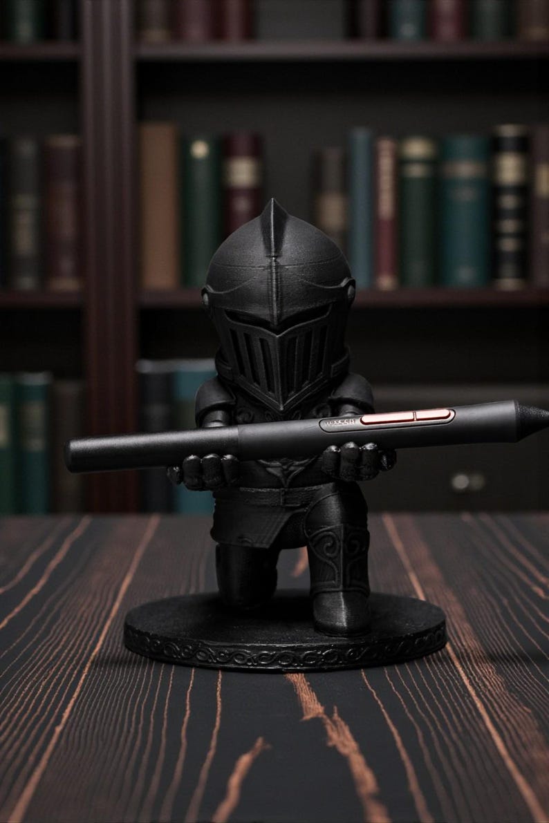 May include: A black knight figurine holding a black stylus with a red accent. The knight is kneeling on a round base with an ornate design. The background features a bookshelf with various books.