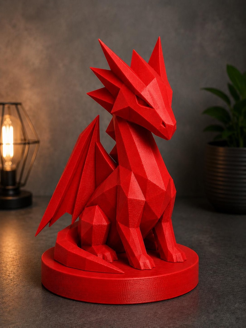 May include: A red geometric dragon sculpture with sharp angles and detailed wings. The dragon is seated on a circular base. The sculpture is a decorative item, suitable for home decor or as a unique gift.