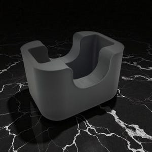 May include: A dark gray, modern-style desk organizer with a curved design. The organizer has a square base and a rounded top with two open sections. The object is made of a smooth material and sits on a black and white marbled surface.