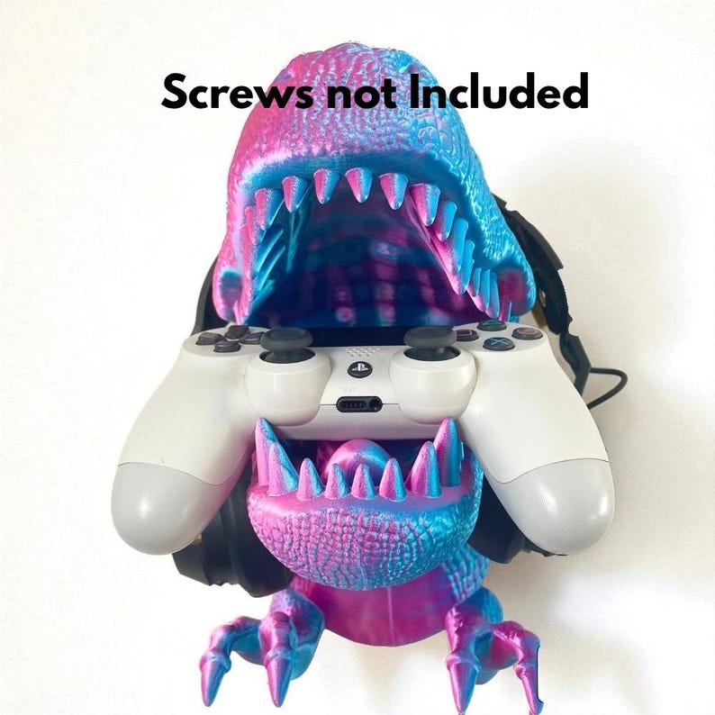 May include: A 3D-printed dinosaur-shaped game controller holder in shades of blue and pink. The holder is designed to cradle a white game controller. The text "Screws not included" is above the dinosaur.