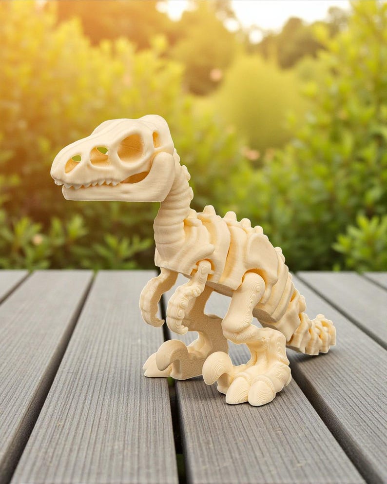May include: A cream-colored dinosaur skeleton toy, featuring articulated joints and a detailed skeletal structure. The toy is posed on a gray wooden surface, with a blurred green background of foliage. The dinosaur's head is turned to the left.