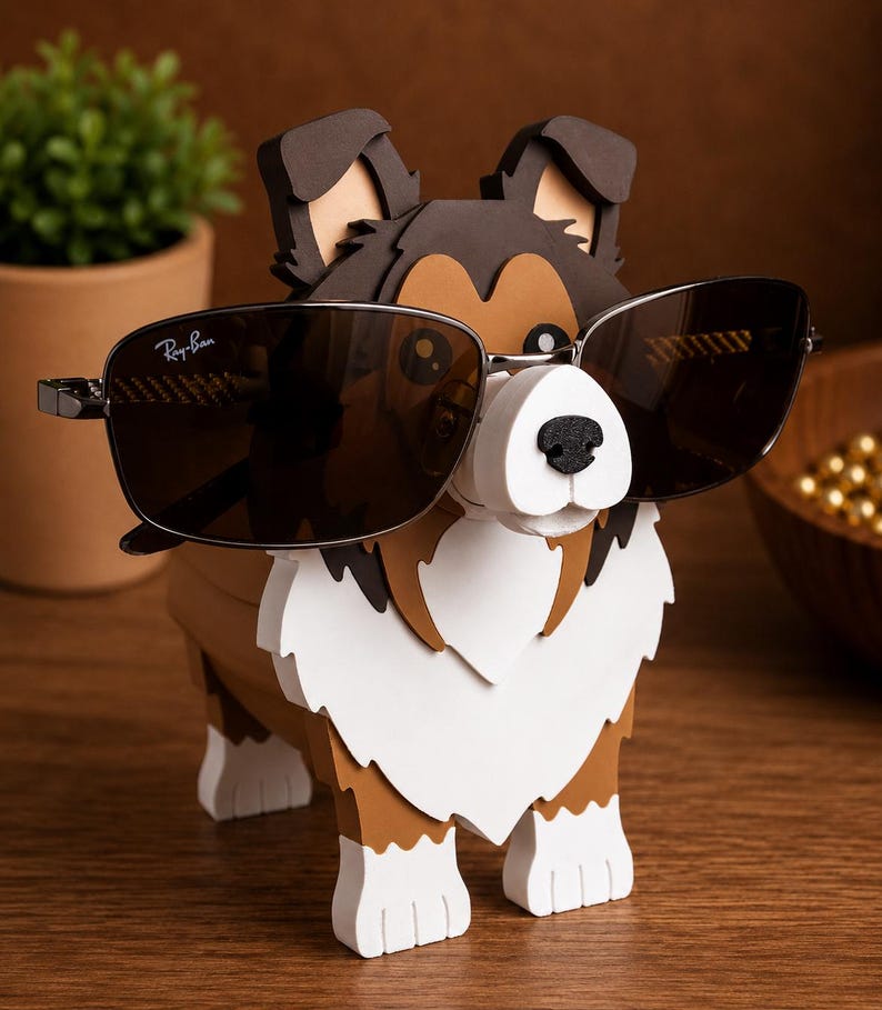 May include: A wooden dog-shaped eyeglass holder with a white, brown, and black color scheme. The dog is wearing a pair of Ray-Ban sunglasses. The holder is on a wooden surface.