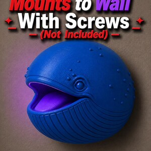 Op de afbeelding: Een blauwe walvisvormige wandlamp met een paarse gloed die uit zijn open mond komt. De tekst "Mounts to Wall With Screws (Not Included)" staat boven de walvis.