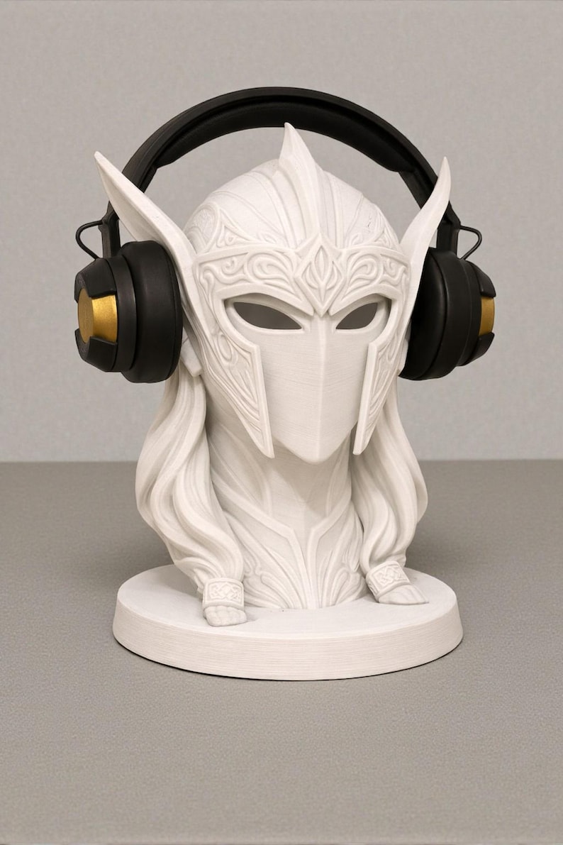 May include: A white bust of a warrior with a helmet and long hair, featuring detailed carvings. Black and gold headphones are placed on the head. The bust sits on a round base, a decorative item.