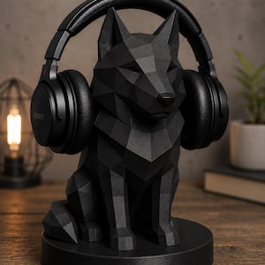 May include: A black geometric wolf-shaped headphone stand holding a pair of black headphones. The stand is made of a matte material and sits on a round base. The headphones have the brand name "SONY" on the side.
