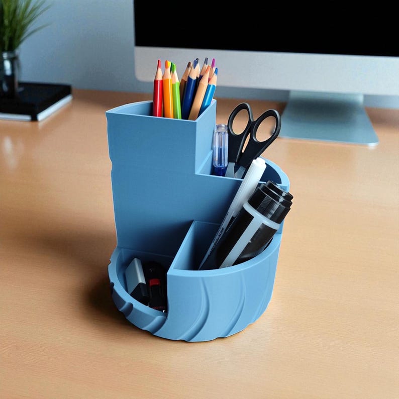 Op de afbeelding: Een lichtblauwe bureau-organizer met meerdere compartimenten. De organizer bevat kleurpotloden, een schaar, een lijmstift en stiften. De bureau-organizer is gemaakt van plastic en heeft een gebogen ontwerp.
