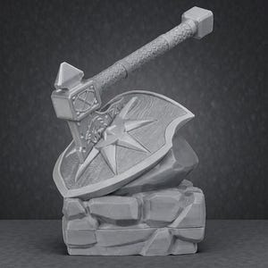 May include: A gray, 3D-printed fantasy axe and shield set. The axe features a textured handle and a hammerhead design. The shield has a starburst pattern and is resting on a stone base, suggesting a miniature display piece.