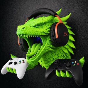 May include: A bright green dragon head wall mount featuring a textured scale pattern and an open mouth. The dragon wears black and orange over-ear headphones and uses its clawed hands to hold a white game controller and a black game controller.