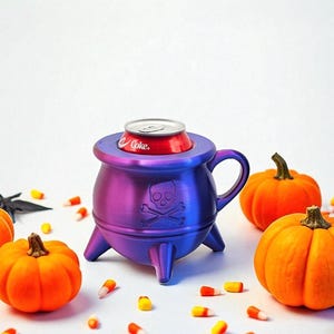 May include: A purple and blue cauldron-shaped can holder with a skull and crossbones design, holding a red Coke can. The Halloween-themed holder is surrounded by orange pumpkins and candy corn.