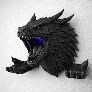 May include: A black dragon head wall sculpture with open mouth and glowing blue light. The dragon has detailed scales, sharp teeth, and horns. The sculpture includes two outstretched clawed hands.