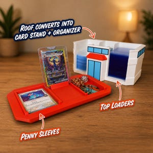 May include: A red card organizer with the text "ROOF CONVERTS INTO CARD STAND + ORGANIZER", "PENNY SLEEVES", and "TOP LOADERS". The organizer has slots for cards, dice, and top loaders. A white card storage unit is also present.