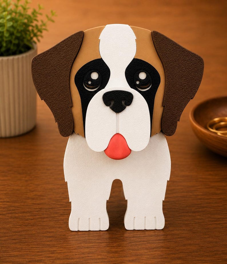 May include: A decorative, three-dimensional Saint Bernard dog figurine. The dog has a white body, brown ears, and a brown and white head. The dog's face features black eyes, a black nose, and a red tongue. The figurine is standing on a wooden surface.