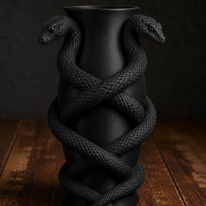 May include: A matte black vase with two snakes coiled around it. The snakes' bodies intertwine, and their heads face outward. The vase has a textured surface and sits on a wooden surface. The snakes have detailed scales.