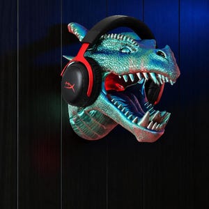 May include: A wall-mounted dragon head sculpture in shades of blue and green, with red accents inside the mouth. Black and red gaming headphones are placed on the dragon's head. The dragon's mouth is open, revealing sharp teeth.